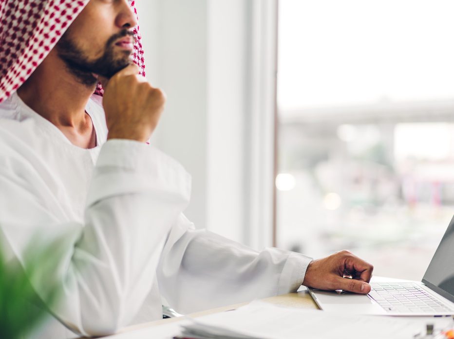 Handsome confident arab businessman working and looking at technology of laptop computer monitor.Creative coworkers arabic business people thinking and planning at modern work loft